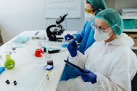 pexels-photo-8539880-8539880 Researchers in PPE work in a lab with glassware and microscopes.